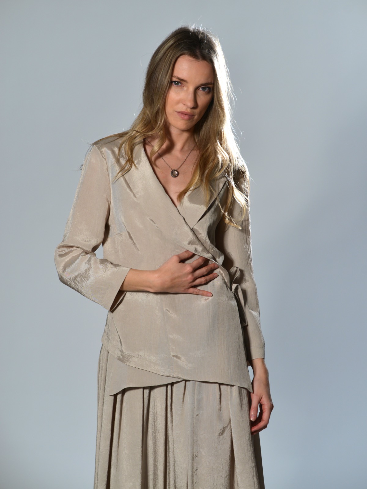 Giacca incrociata Marina Lari in acetato color beige, con rever ampio, chiusura laterale con laccetto e fondo asimmetrico