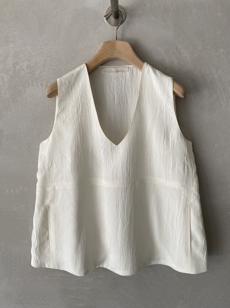 Top oversize Marina Lari in acetato bianco, con scollo a V profondo, tasche laterali a marsupio e linea svasata