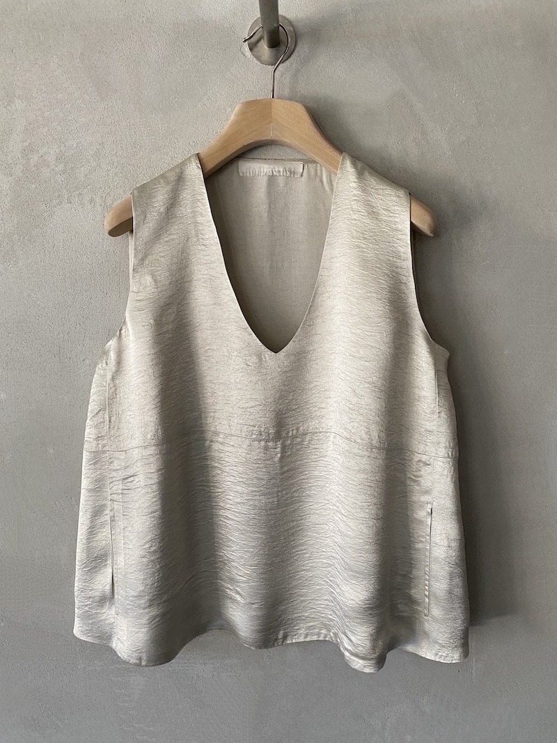 Top oversize Marina Lari in acetato greige, con scollo a V profondo e tasche laterali a marsupio