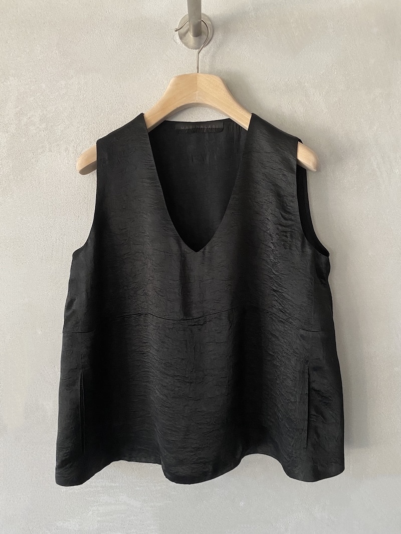 Top oversize Marina Lari in acetato nero, con scollo a V profondo e tasche laterali a marsupio