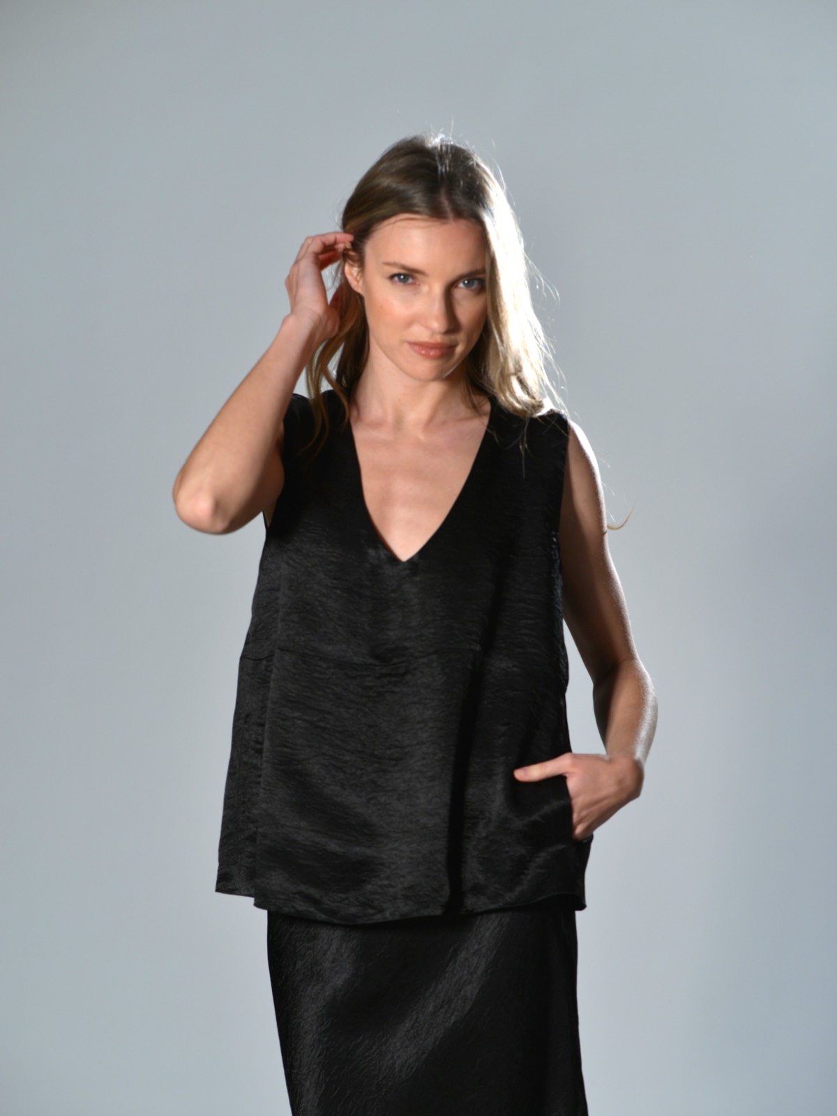 Top oversize Marina Lari in acetato nero, con scollo a V profondo e tasche laterali a marsupio