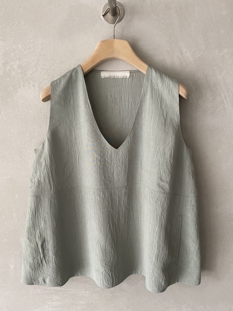 Top oversize Marina Lari in acetato color salvia, con scollo a V profondo, tasche laterali a marsupio e linea svasata