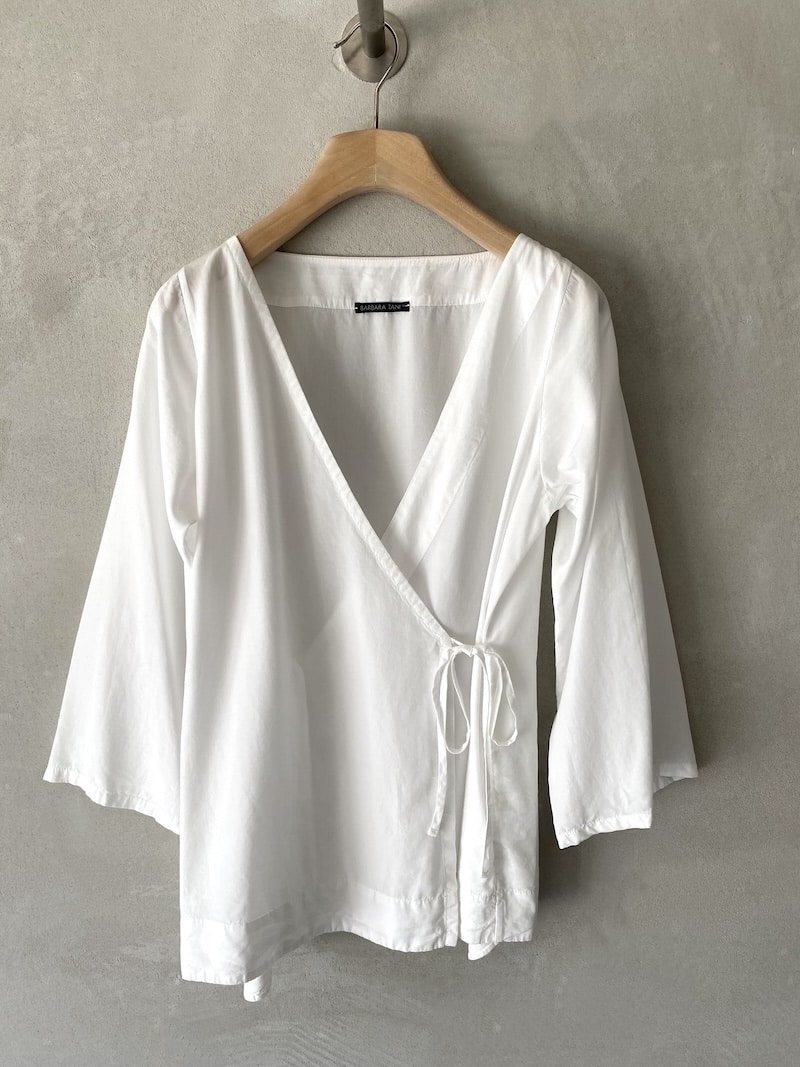Camicia incrociata in lyocell con scollo a V e chiusura a portafoglio con laccetti laterali, maniche a 3/4 e tasche laterali inserite in cucitura, colore bianco latte – Barbara Tani