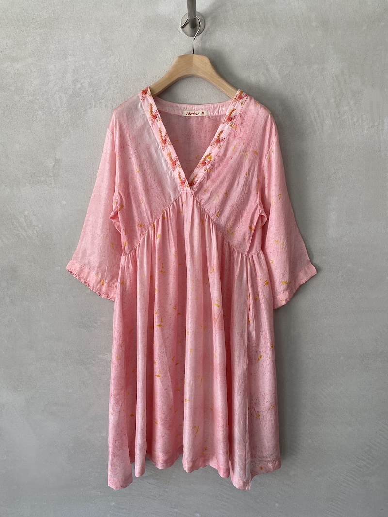 Abito rosa in seta habotai dipinta a mano, scollo a V con bordo ricamato, spalla scesa, manica lunga ampia a kimono, linea svasata con arricciatura sotto il seno, tasche laterali, lunghezza sopra il ginocchio, vestibilità morbida Nimbu