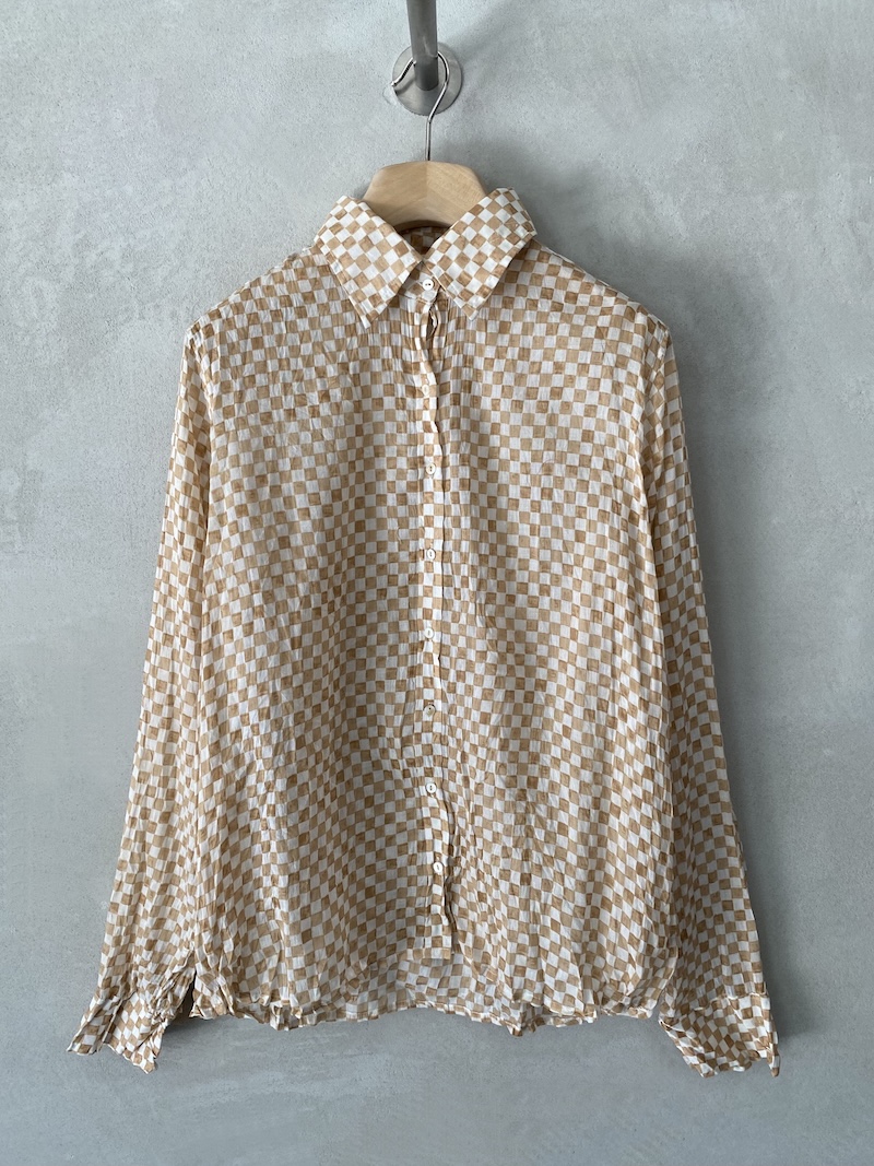Camicia beige in mussola di cotone con stampa a quadretti, texture leggermente stropicciata, colletto classico, maniche lunghe con polsino e bottone, apertura frontale con bottoni, vestibilità over Nimbu