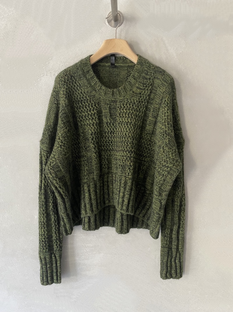Oversized boxy green merino wool sweater with mixed knit stitches, round neck, dropped shoulders and longer hem at the back, Serie Numerica.
