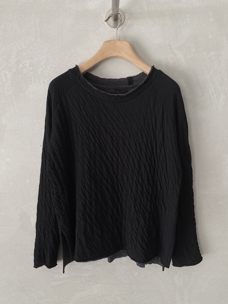 T-shirt boxy nera in maglina goffrata e doppiata, con maniche lunghe raglan, spacchi laterali e finiture a taglio vivo, Marina Lari.